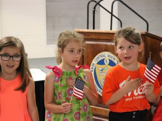 Students hold mini flags while reciting the Pledge at the Knox County Board of Education meeting.