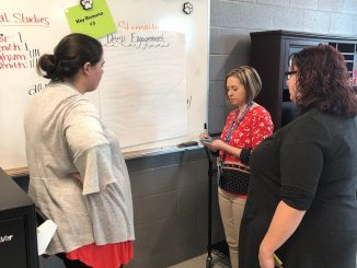 Teachers are shown in a gallery walk addressing ways to engage students.