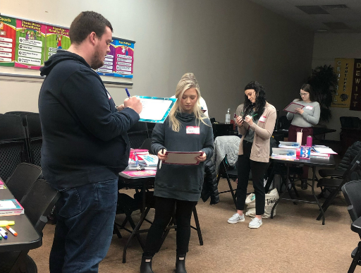 Two teachers are shown in the foreground participating in a Kagan activity where they are sharing information.